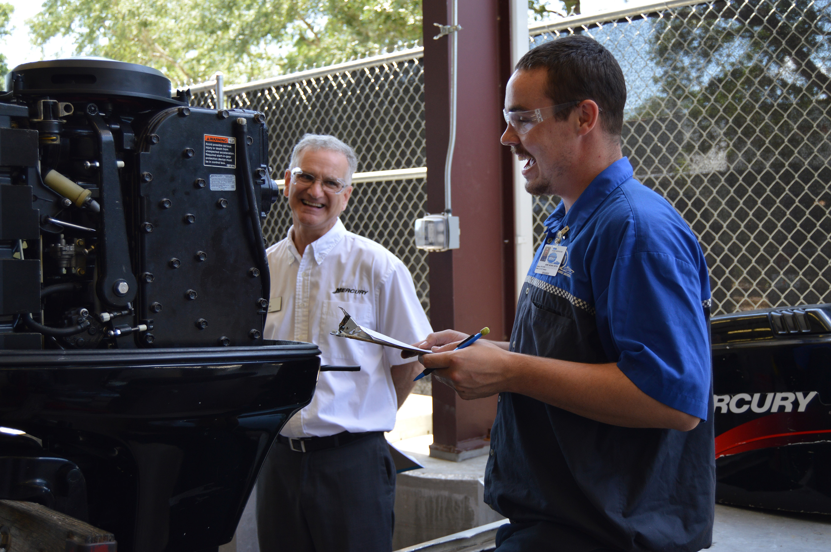 (L to R)  Tom Miller, Director of Service Training, Mercury Marine Corporation, discusses the new provisional certification program for Mercury outboard motors with Marine Mechanics Institute (MMI) student Levi Hodson.  MMI is the only career technical education school in the country with which Mercury Marine is offering this certification program.