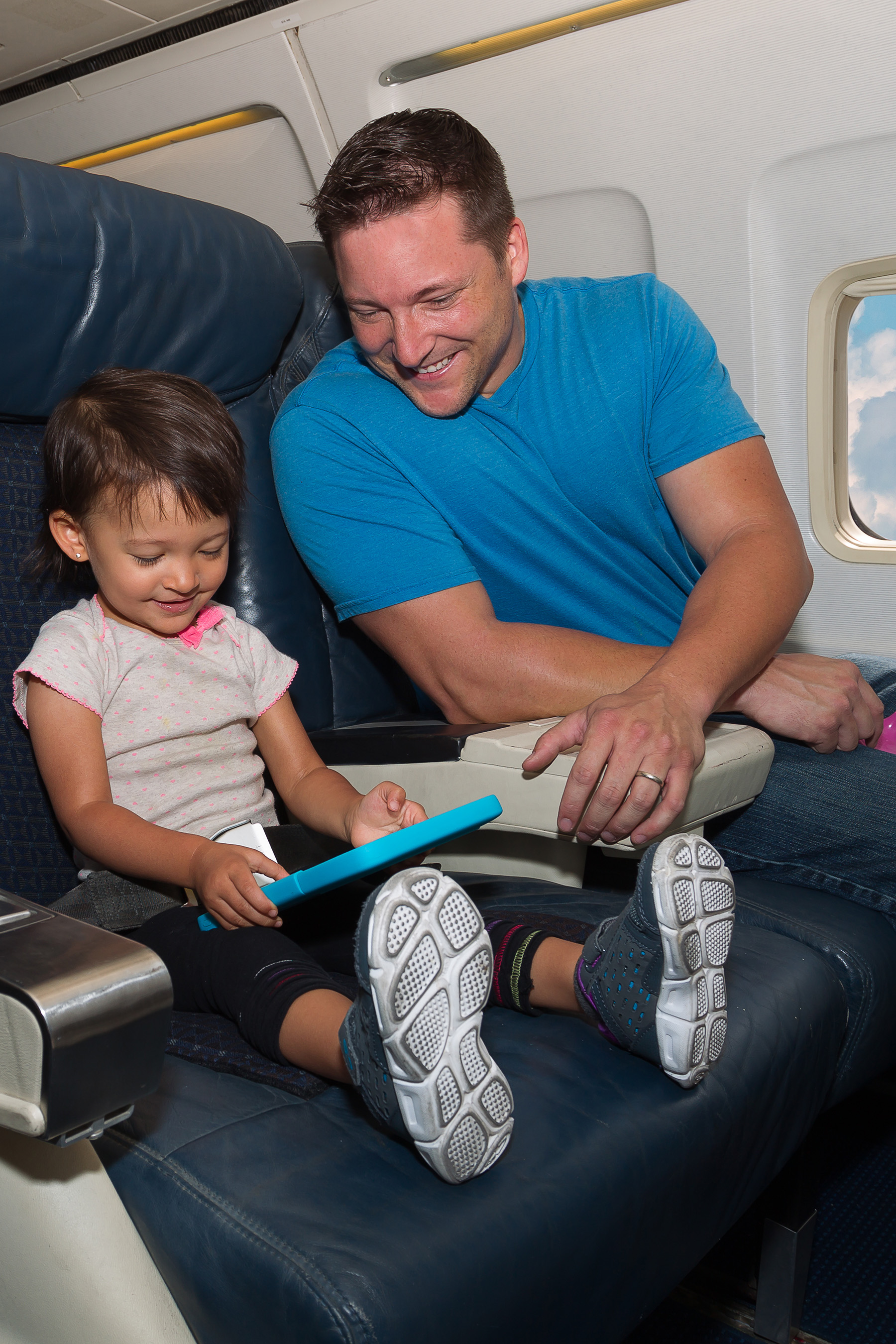 Little girl playing on tablet with father in cabin