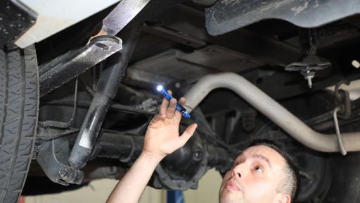 A professional preforming an inspection on a vechicle with a flashlight