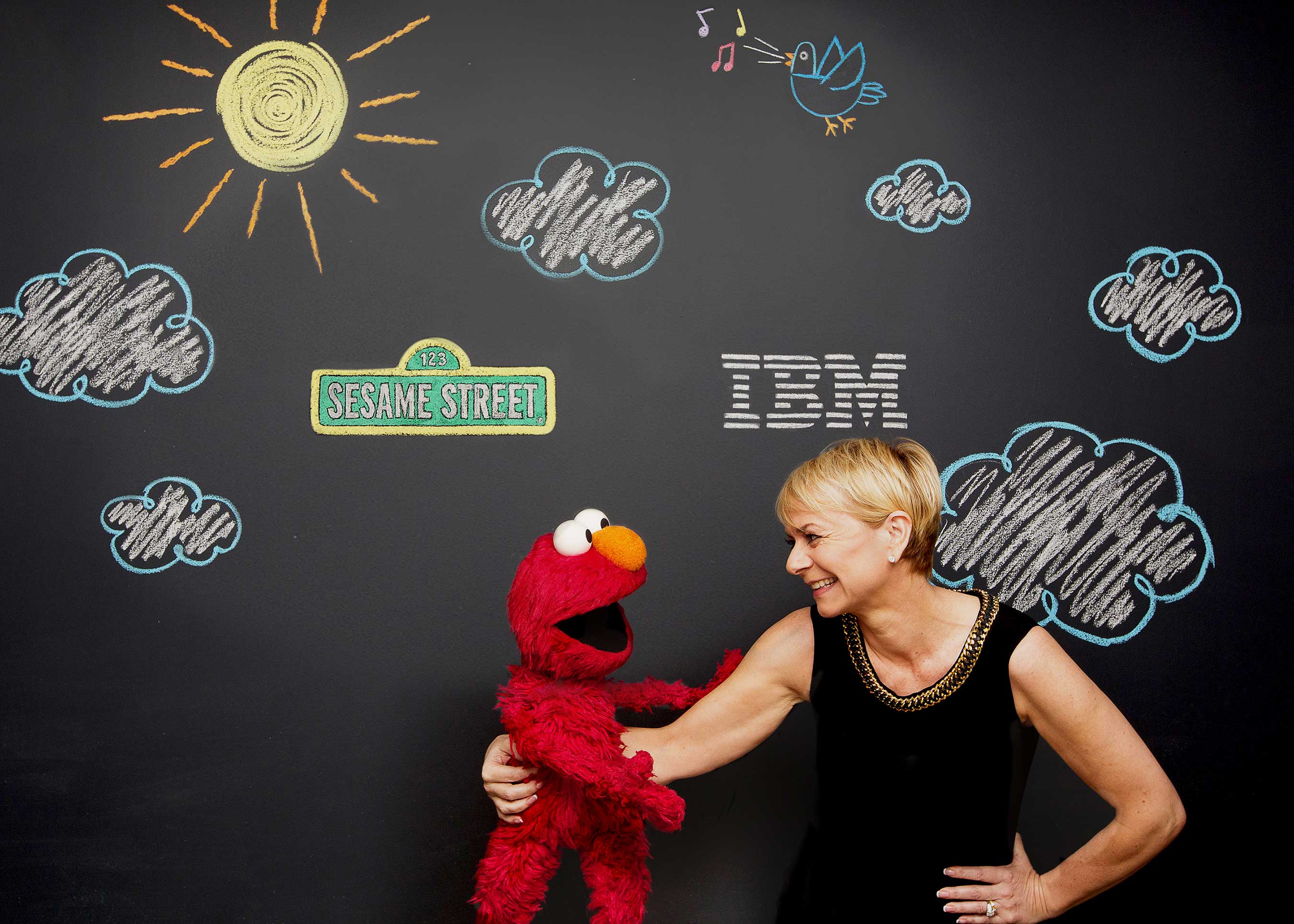 As part of a three-year agreement, Sesame Workshop and IBM Watson are developing a new category of educational products that aim to adapt to the learning styles and aptitudes of individual preschoolers. Pictured here are Harriet Green, IBM General Manager of Watson Internet of Things, Commerce and Education, and Elmo, 3 1/2 year old monster. (John O'Boyle, Feature Photo Service for IBM)