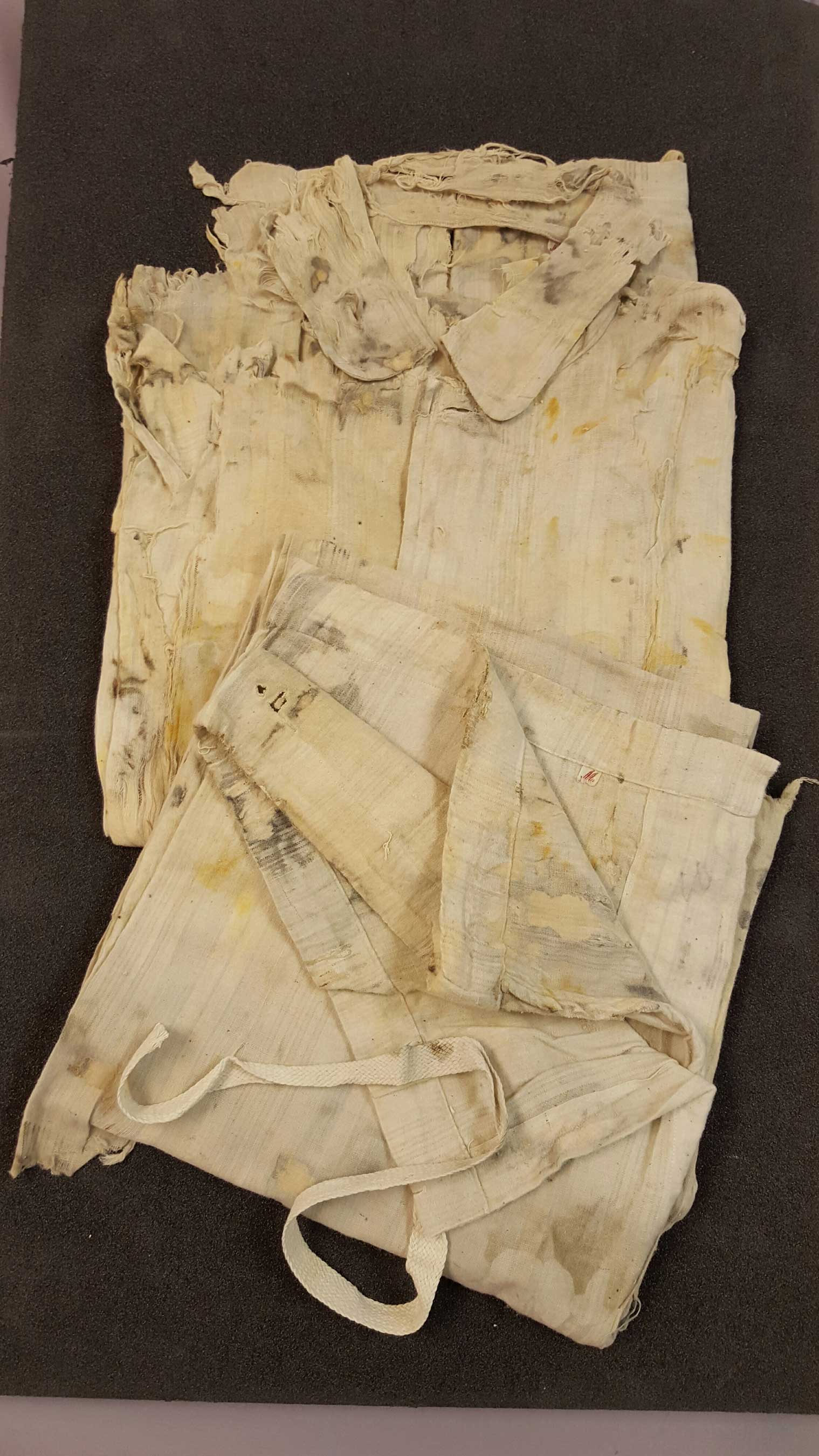 This pair of men’s pajamas is made of white cotton with blue stripes. No maker marks were found, they are a size medium with button shirt and drawstring bottoms. (Credit Premier Exhibitions)