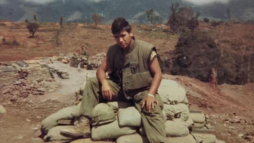 Bill Rider in fatigues sitting on top of sandbags in Vietnam.