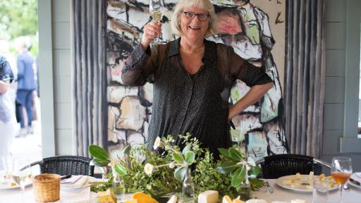 Women holding glass of wine, standing behind table with platters of cheese