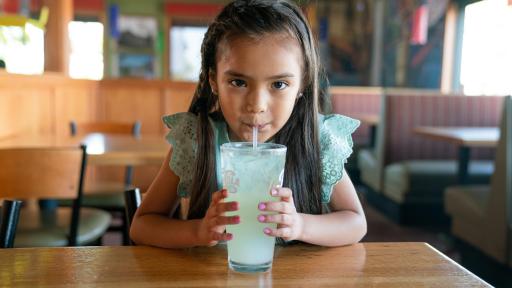 Young girl sipping lemonade through a straw.