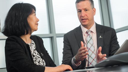 Man and woman in business attire are discussing something while sitting at a table.