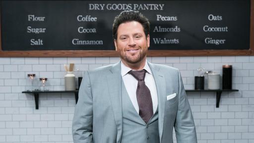 Host Scott Conant posing for photo in set kitchen