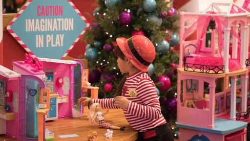 Little girl playing with a Barbie DreamHouse.