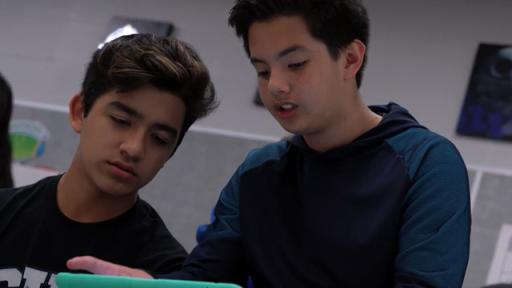 Students studying robotics on a tablet.