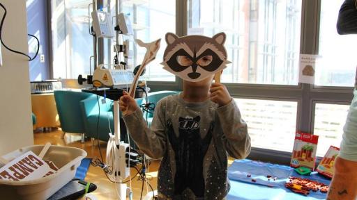 Young boy covering up his face with raccoon mask