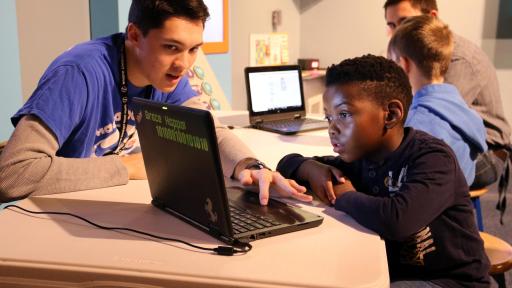 Teacher helping kid on computer