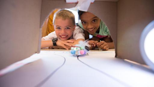 boy and girl pictured with optibot - a small self-driving robot that senses changes in light