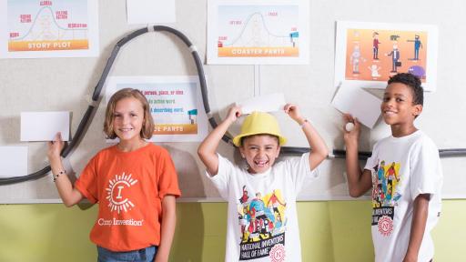 Girl and two boys stand in front of their invention