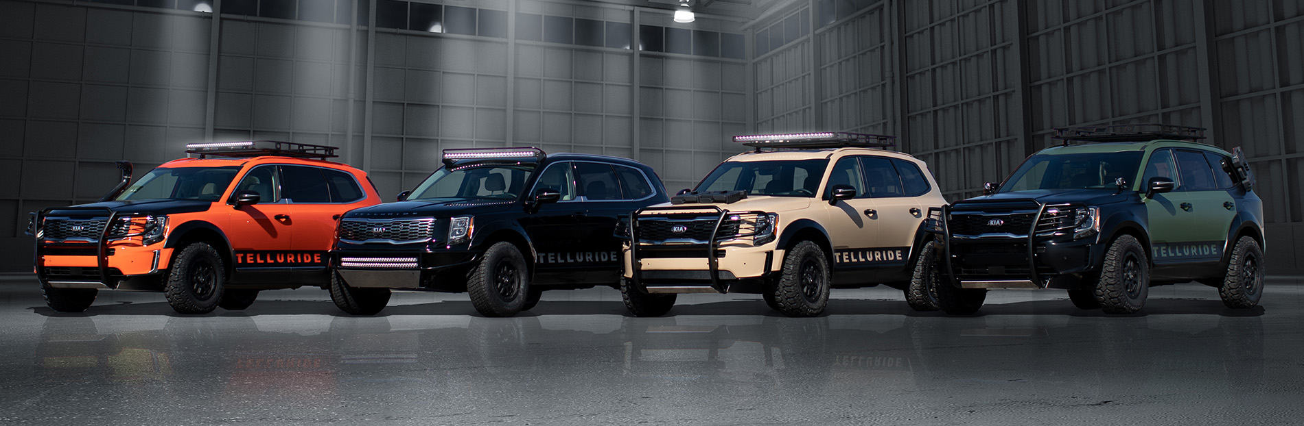 A row of 4 Kia Telluride SUV's in different colors inside a building.