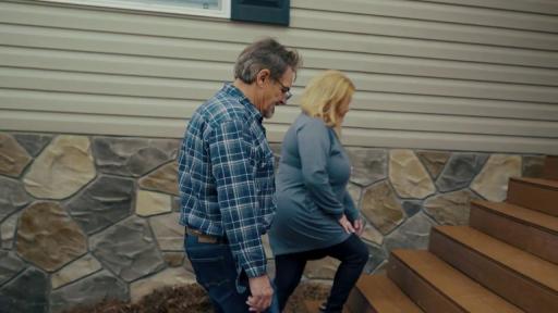 Man and woman walking up steps to new home.