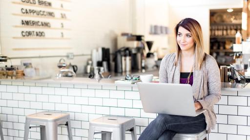 Woman with laptop sitting at a counter.