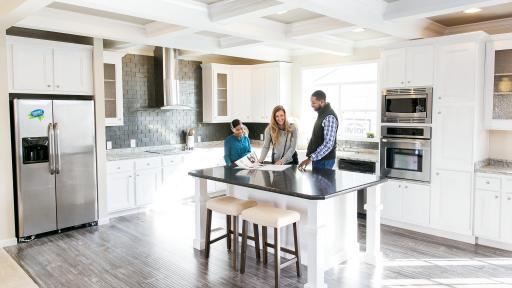 A couple looks over papers atop a counter in a brand new kitchen.