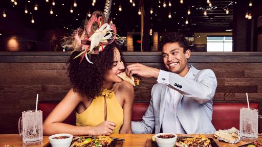 Man feeding a woman a fajita.