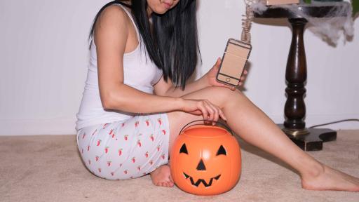 Girl holding a cardboard phone and sitting next to a pumpkin bucket