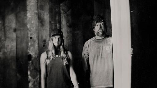 A man and a young woman with a surfboard and sander