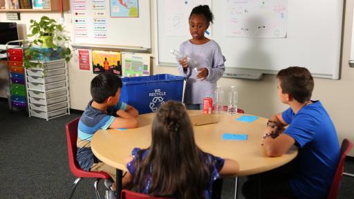 Children putting recyclables into a recycling bin