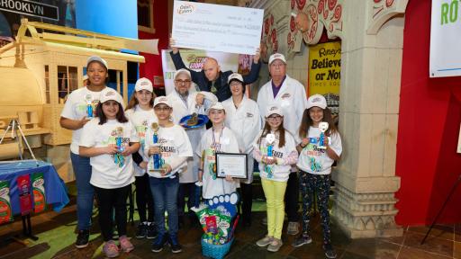 Contestants holding their prizes, with reward check for $2,500 held high.