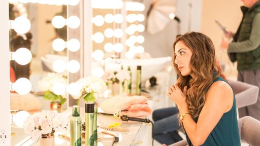 Blond model sitting in front of a mirror with Suave product.