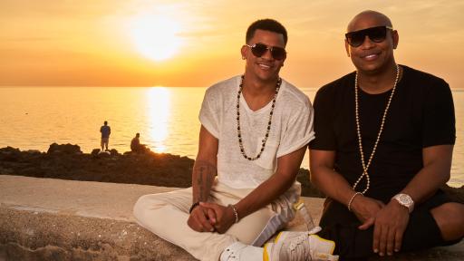 Gente de zona members, Alexander Delgado and
Randy Malcom, sitting on a wall near a beach
