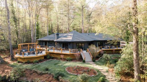The backyard, which has a staircase leading down from the patio to a stepping-stone walkway. There is a small pond near the house.