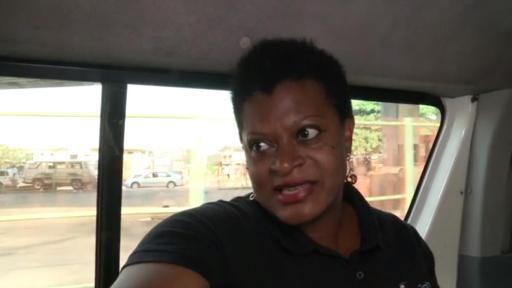 African woman on a bus talking to the camera