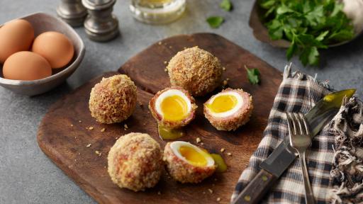Scotch eggs cut in half with yolk running out.