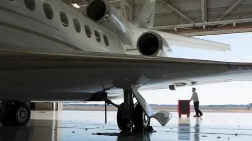 Man wheeling a tool chest near a plane