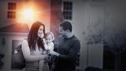 Couple holding baby in from out house with sun shining