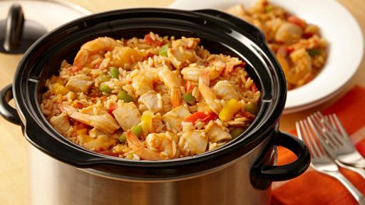 Crockpot filled with chicken, shrimp, rice and minced vegetables.