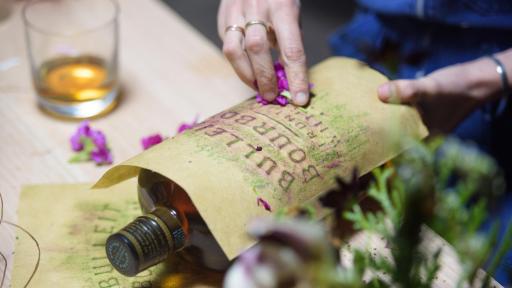 Woman rubbing flowers on a paper for a bottle impression.