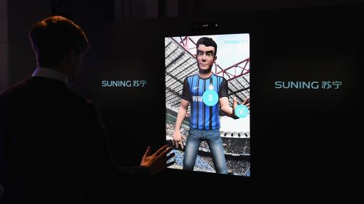 Man interacting with an avatar on a screen. The avatar is in a soccer stadium full of people and is wearing a soccer jersey.