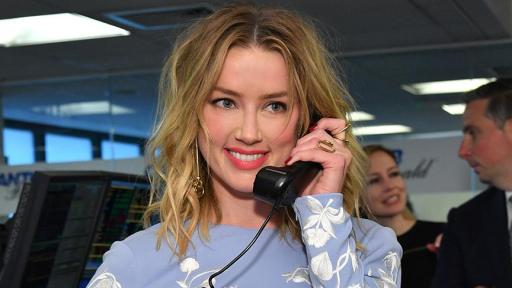 Amber Heard picking up a phone smiling into the camera