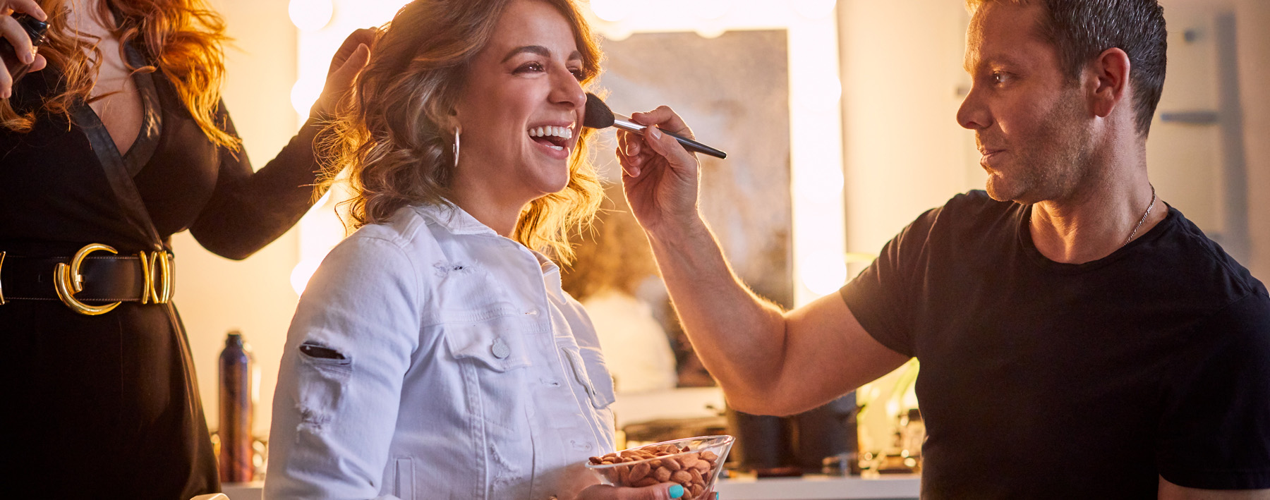 Victoria Arlen holding a bowl of California Almonds while in the makeup chair.