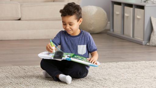 A young boy sits on the floor playing with his LeapFrog.