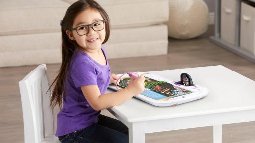 Little girl playing with the LeapStart 3D while she sits at a child's table.