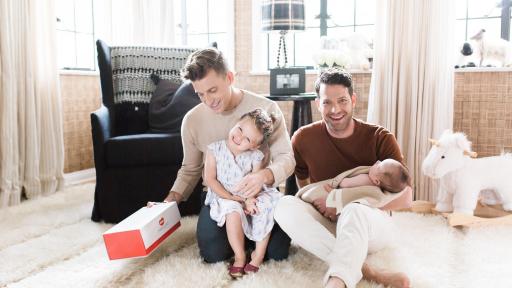 Two men sitting on carpet with a baby.