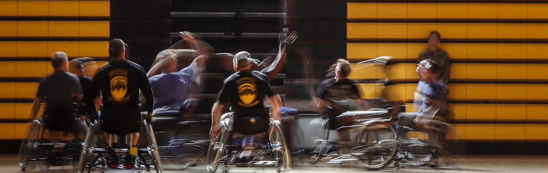 Group of men in wheelchairs playing basketball in a gym.