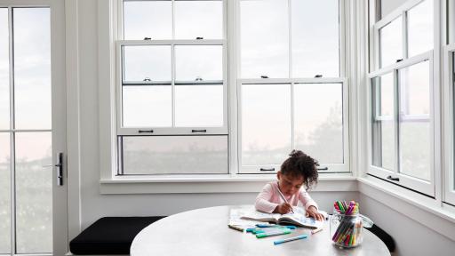 Child coloring on a table beside a large Pella Window