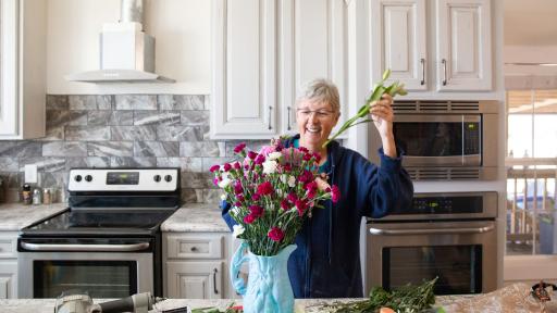 Woman putting flowers in a vase, in her new kitchen.