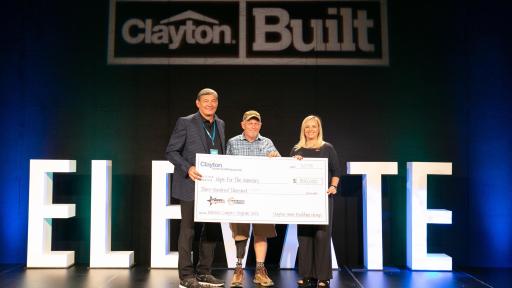Three people on a stage holding a giant check.