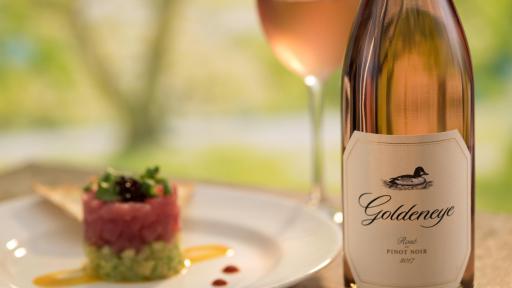 Wine bottle beside a plate of sushi.