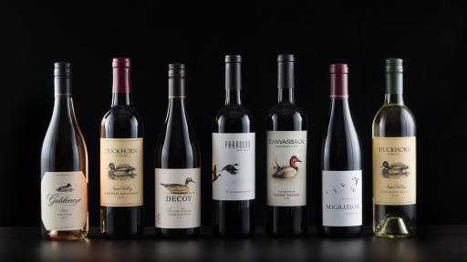 The Seven Masterful Wines standing lined up against a black background.