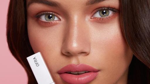 Female model holding up lip cosmetics.