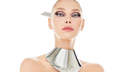 Woman with eyeshadow and a large metal necklace.