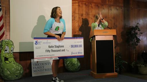 Woman holding a check for $50,000 and laughing.