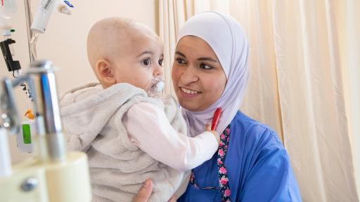 Female nurse holding child in hospital